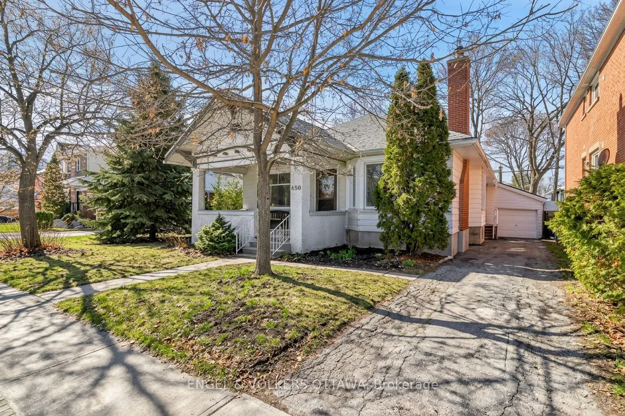 A white, one-story house with a front porch and a brick chimney on a sunny day. A tree is in front of the house.