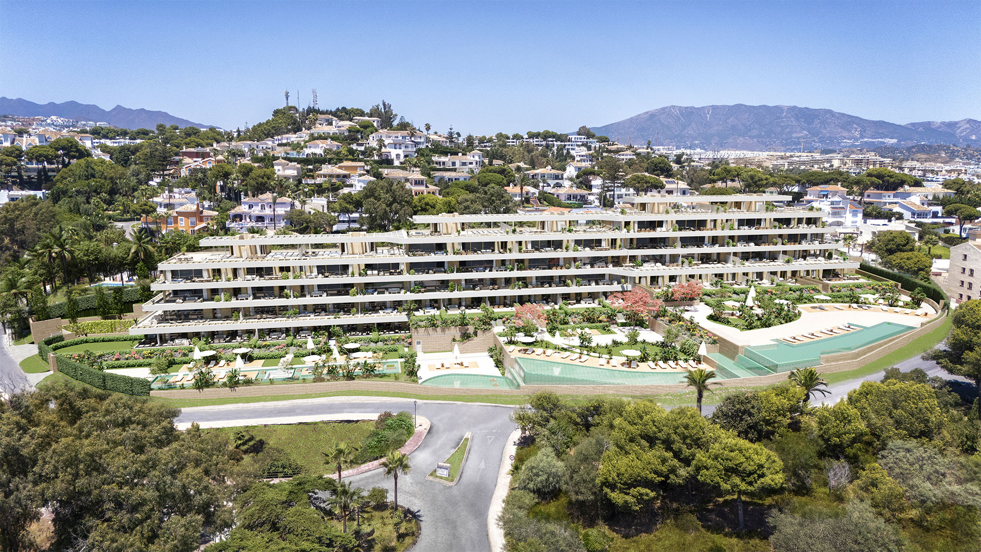 Aerial view of a modern terraced apartment complex with multiple swimming pools, lush gardens, and mountain views.