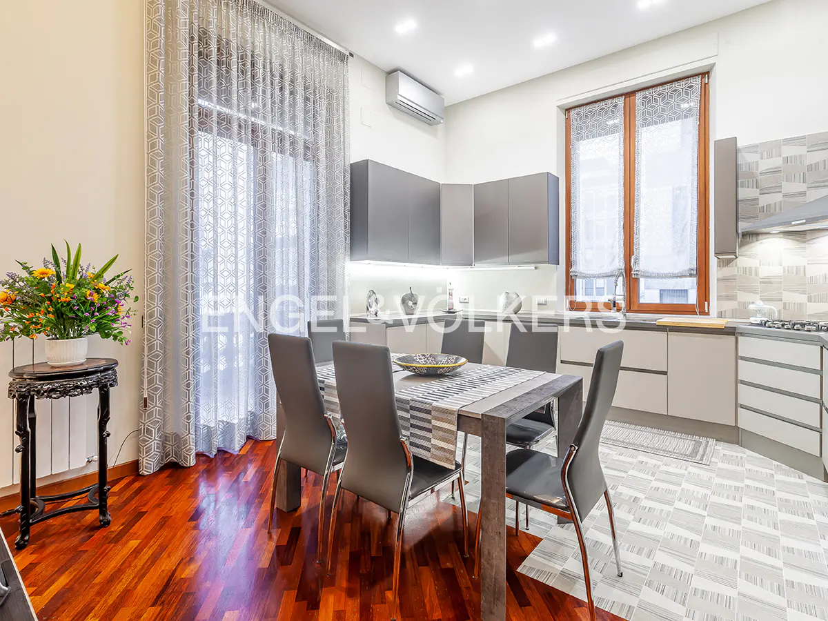 A modern kitchen and dining area with gray cabinets, a wooden table with six chairs, and a bouquet of flowers.