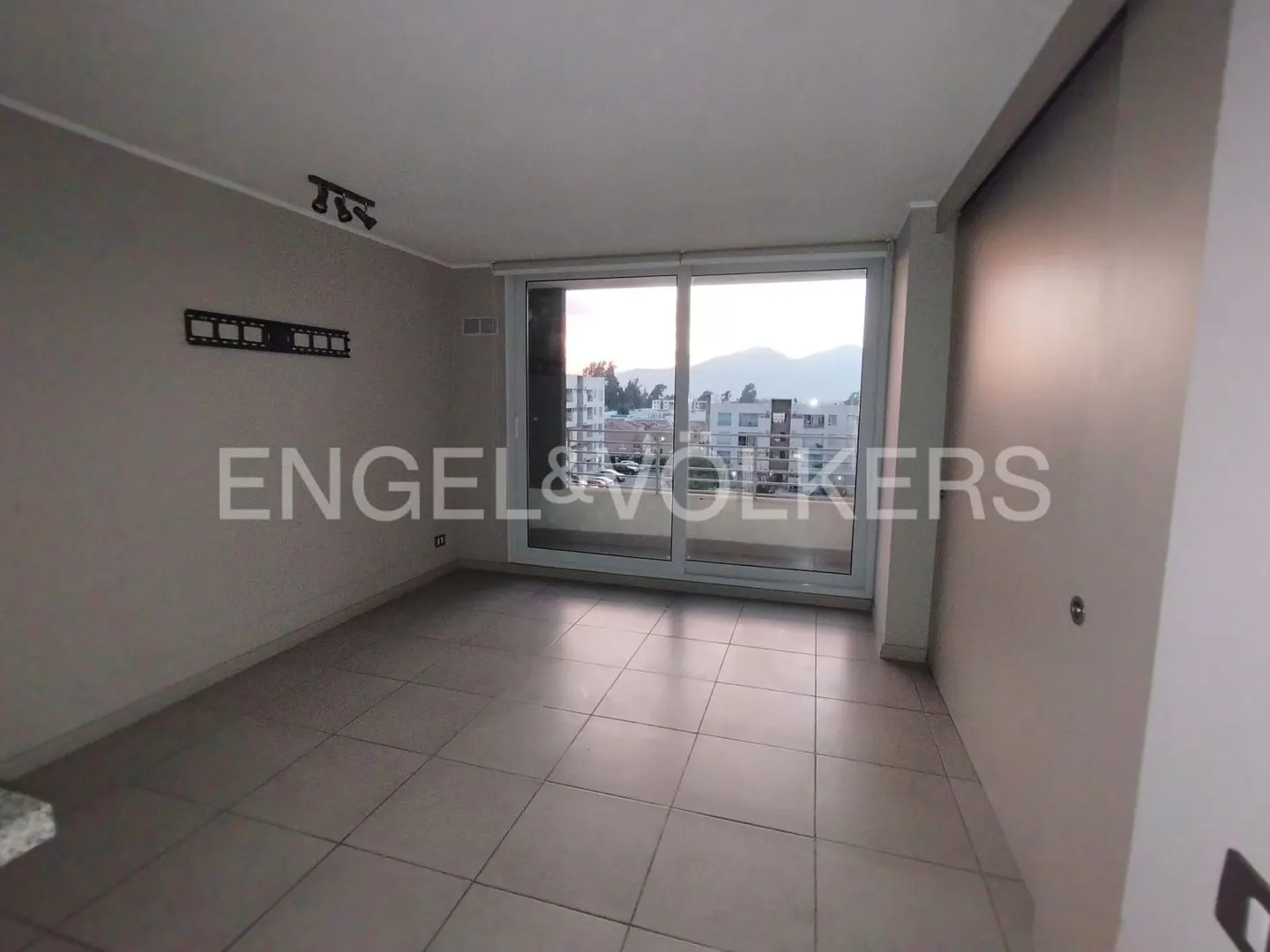 Empty room with gray tile floor, light gray walls, and a sliding glass door to a balcony with a city view.