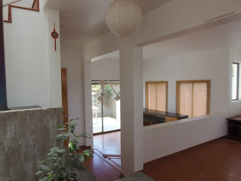 Interior view of a white-walled home with a paper lantern, plant, and open floor plan.