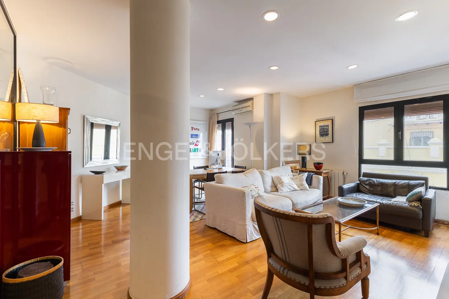 Bright living room with hardwood floors, a white sofa, a dark leather loveseat, and a central structural column.