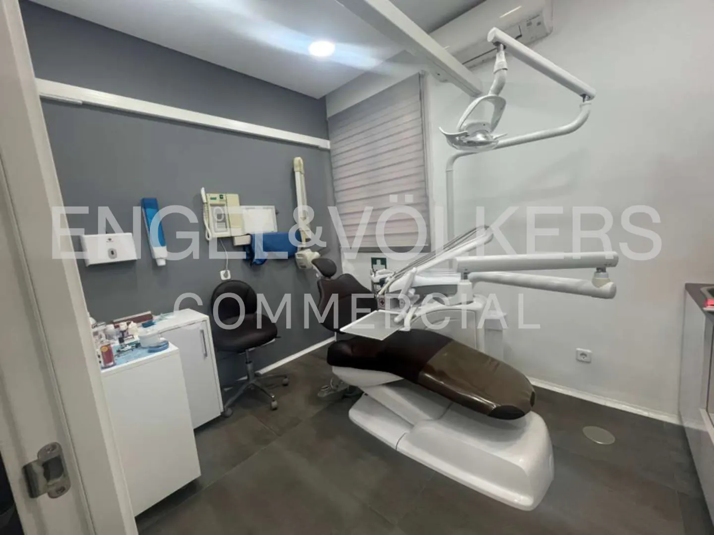 A dental office with a chair, equipment, and gray walls.