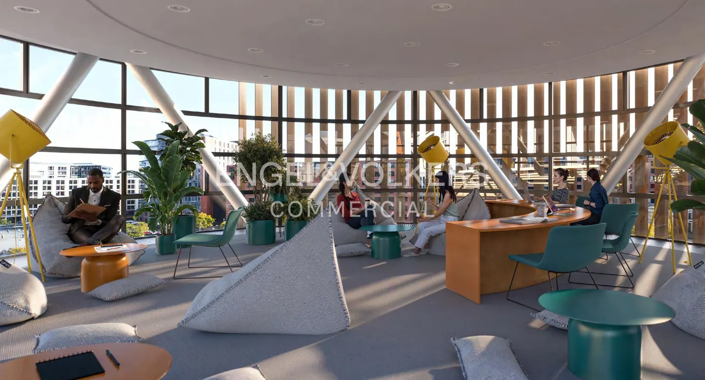 Open office space with people working, beanbag chairs, plants, and large windows.