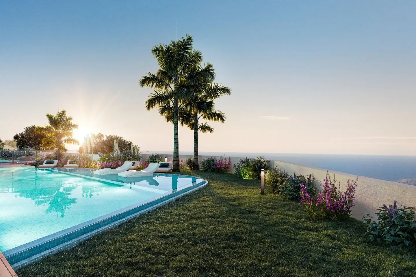 A turquoise pool with white lounge chairs sits near palm trees and a grassy lawn overlooking the ocean at sunset.