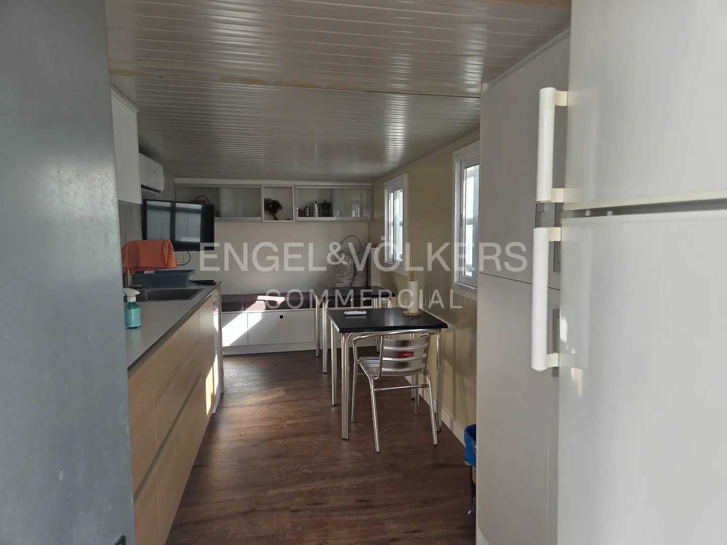 A kitchen with a table and chairs, light wood cabinets, and a white refrigerator.