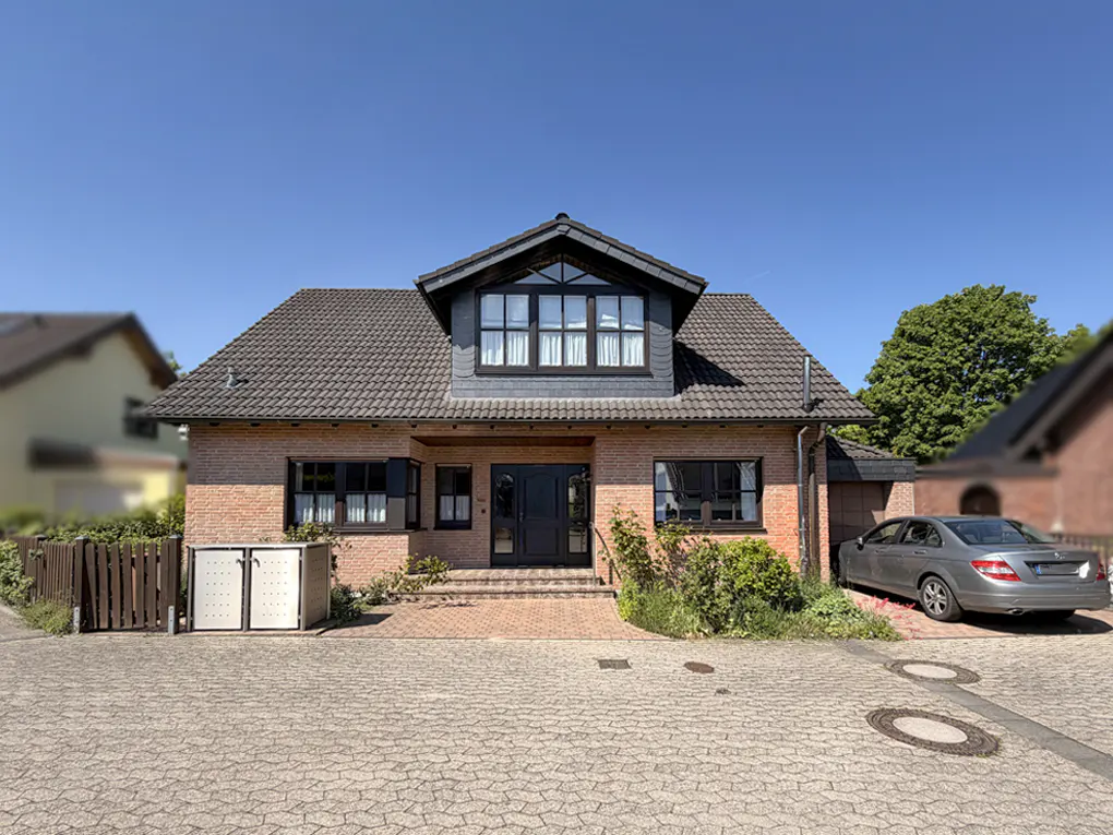 A brick house with a gray roof and black trim, a car parked in the driveway.