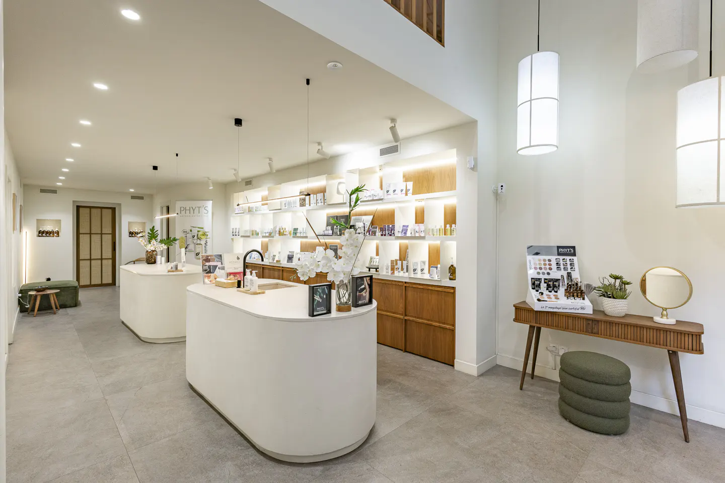 Bright, modern store interior with white counters, wood shelves stocked with products, and pendant lights.