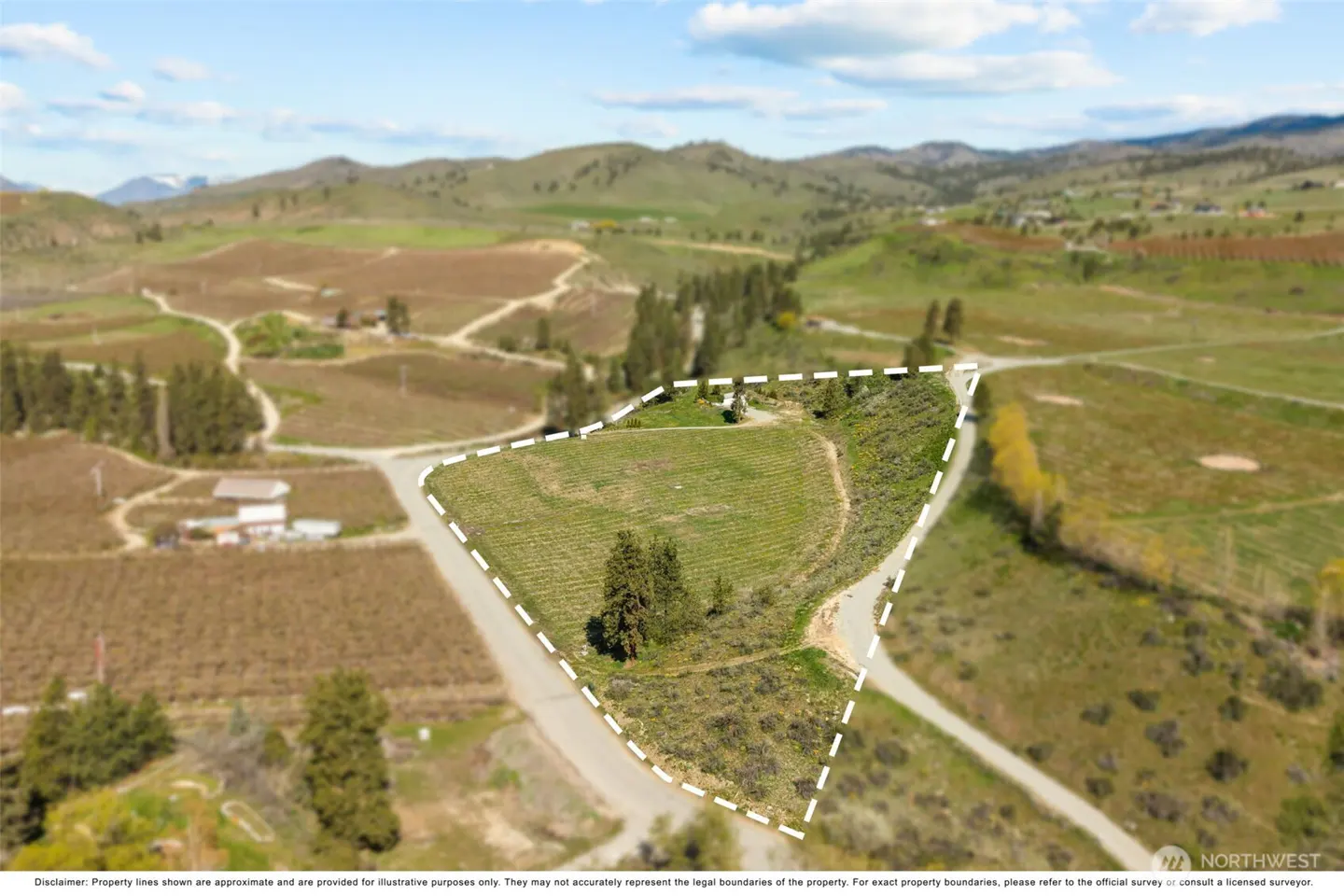 Aerial view of a vacant lot outlined in white, surrounded by green hills and vineyards under a blue sky.
