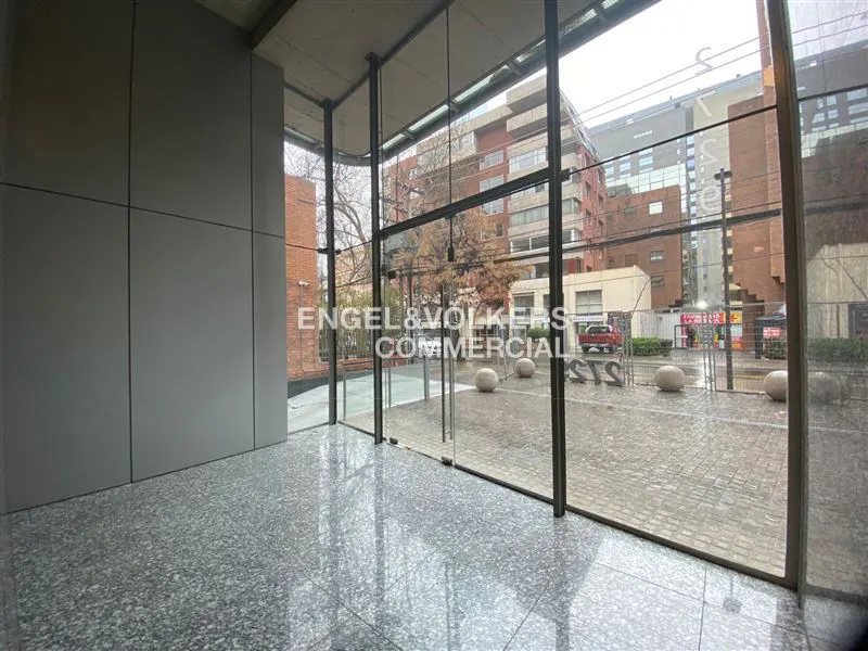 A commercial space with gray walls, a speckled floor, and a glass wall overlooking a city street.