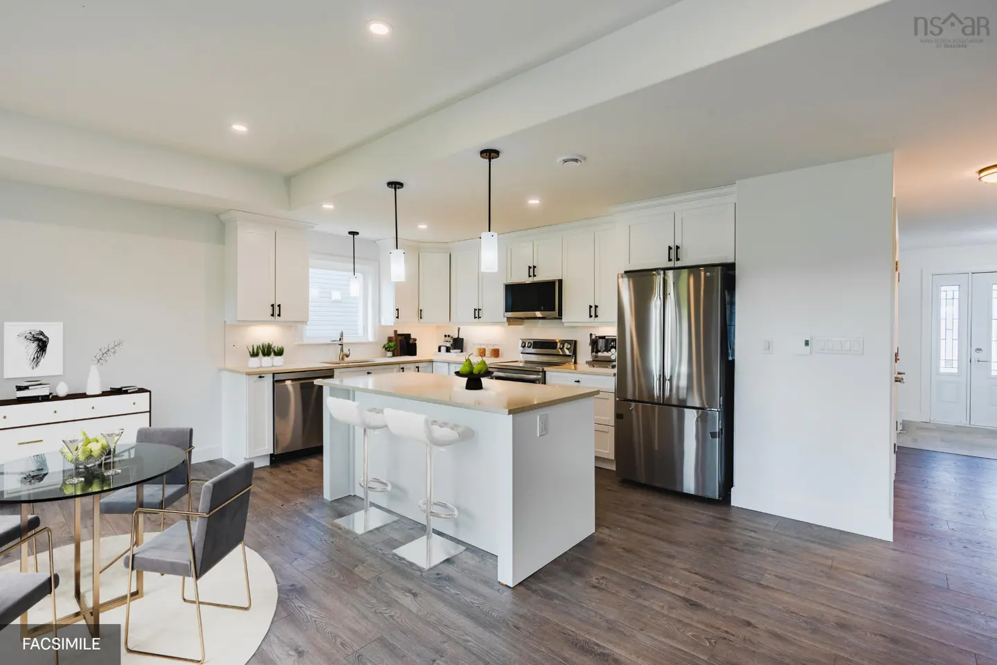 A bright, modern kitchen with white cabinets, stainless steel appliances, and a central island with seating. A dining area is visible with a glass table.