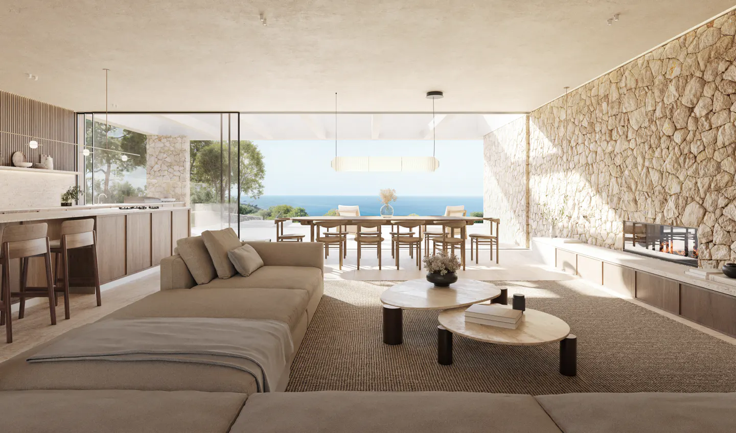 A bright, modern living room with a beige sofa, stone wall, and ocean view. A dining table and kitchen are visible in the background.
