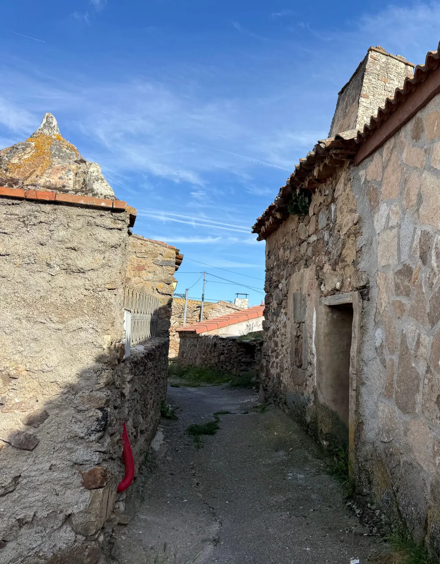 Narrow street view between old stone buildings under a blue sky.