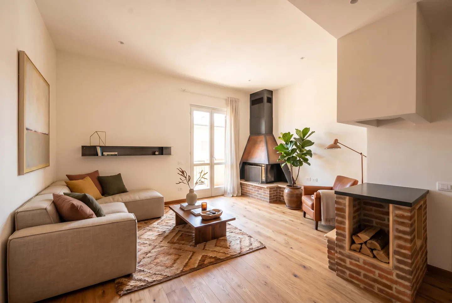 Living room with a beige sectional sofa, wood floors, and a brick fireplace. A brown rug sits under a wood coffee table.