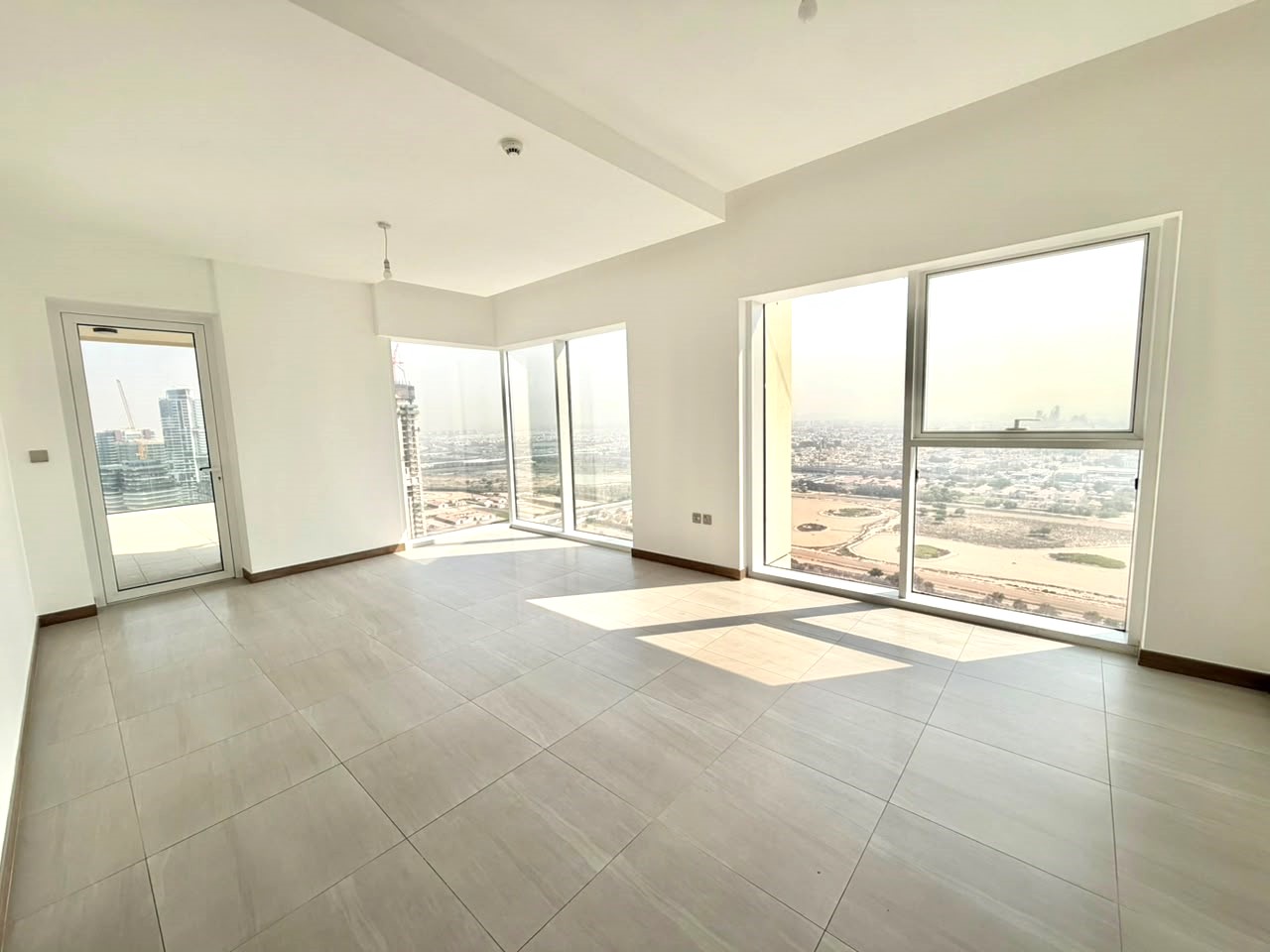 Bright, empty room with white walls, light tile floors, and large windows offering a panoramic city and desert view. [AI-generated text]