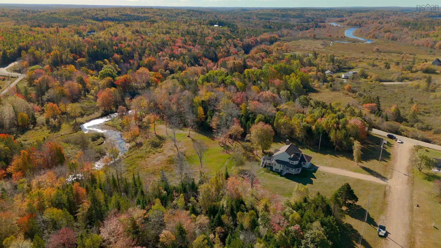 Aerial view of a large house surrounded by colorful fall foliage and a winding river.
