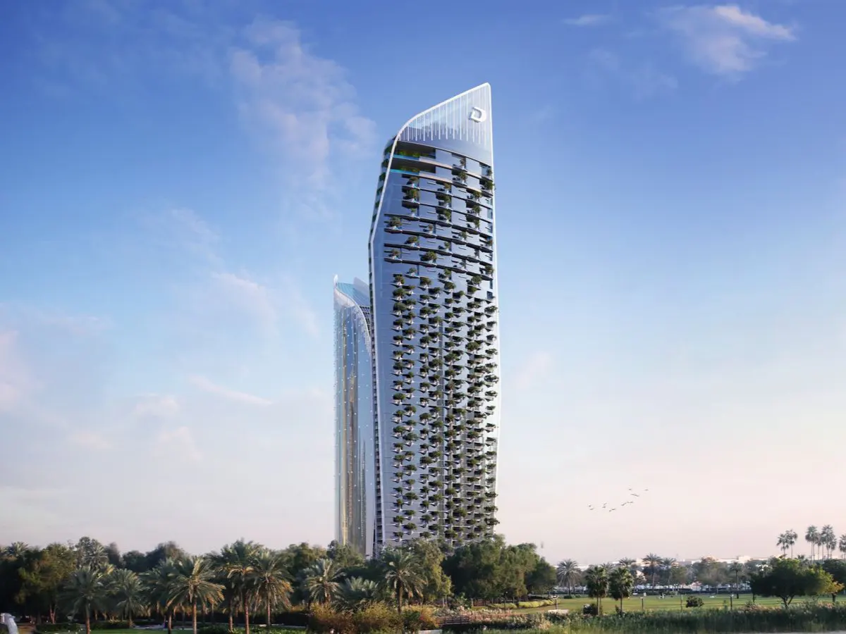 Modern, curved glass skyscrapers with greenery on balconies, set against a blue sky and lush green landscape.