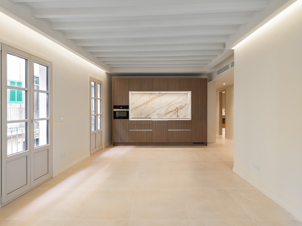 Modern kitchen with wood cabinets, marble backsplash, and white beamed ceiling in a bright, open-plan living space. [AI-generated text]