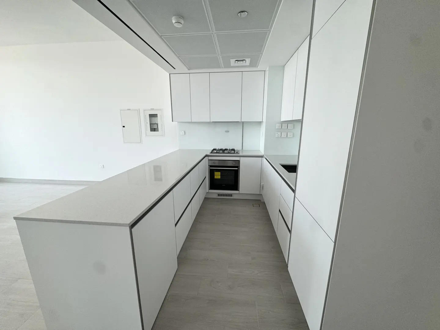 A modern, all-white kitchen with sleek cabinets, countertops, and stainless steel oven.