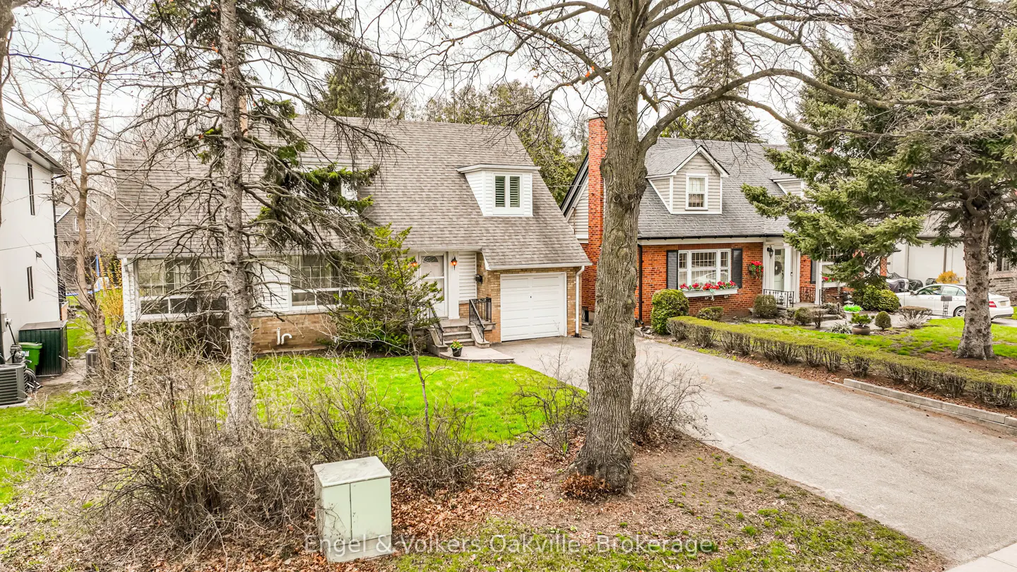 Exterior view of two houses with gray roofs, green lawns, and bare trees in the front yard.