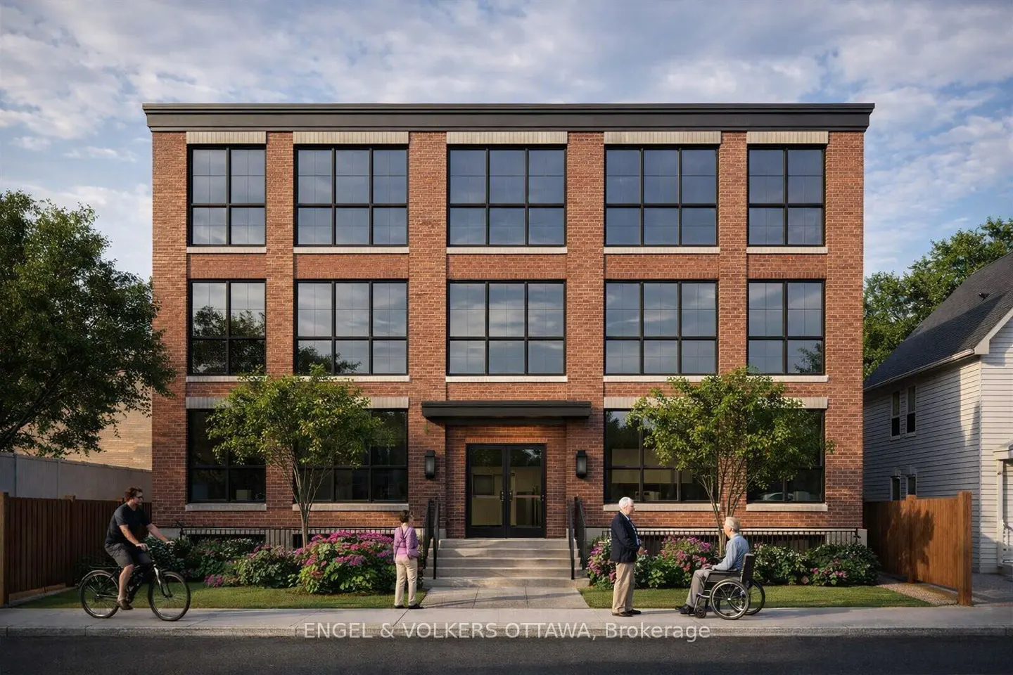 Three-story brick apartment building with black framed windows. People on the sidewalk, including one in a wheelchair and a cyclist.