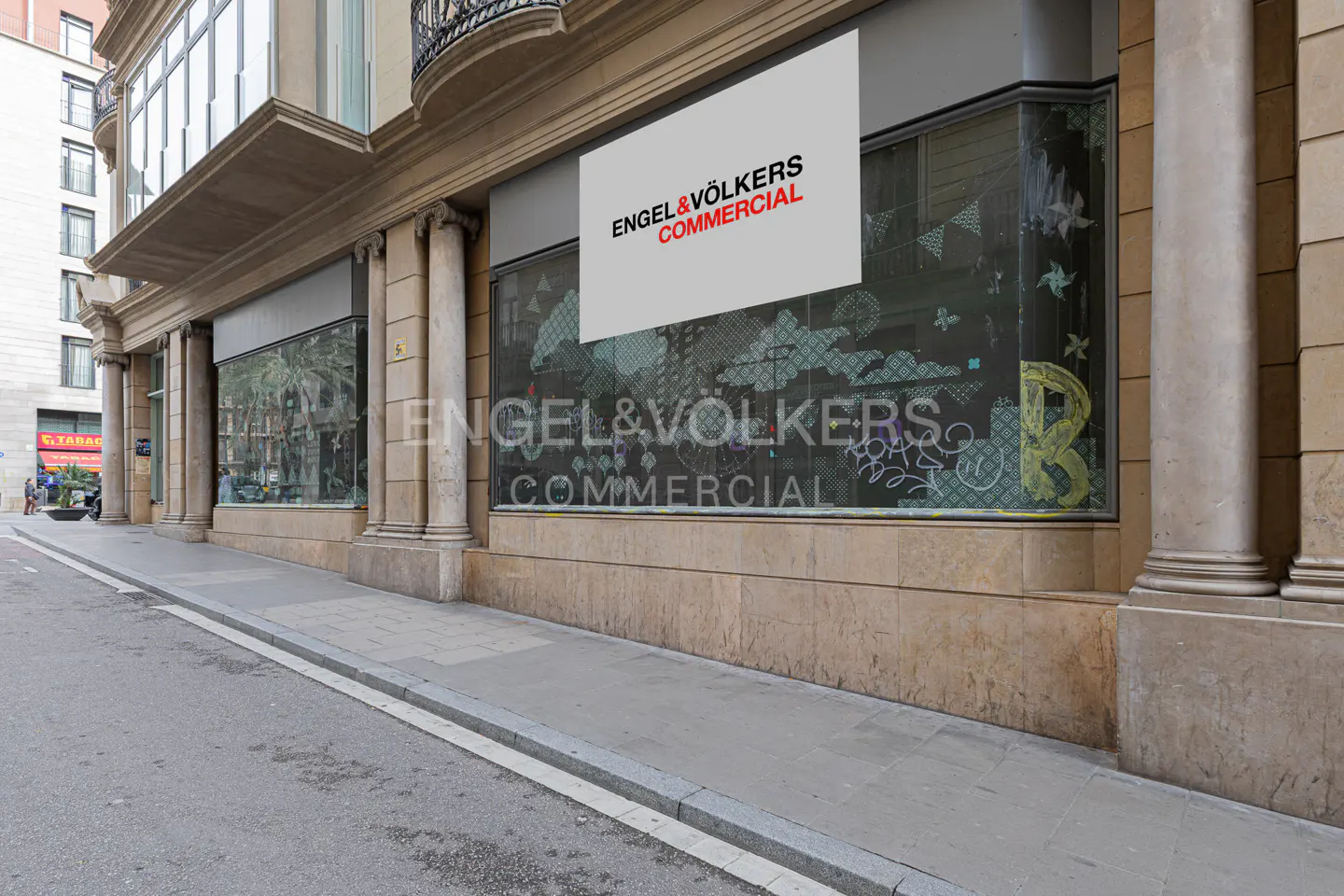 Exterior view of Engel & Völkers Commercial office with large windows and signage. The building is tan stone with columns.