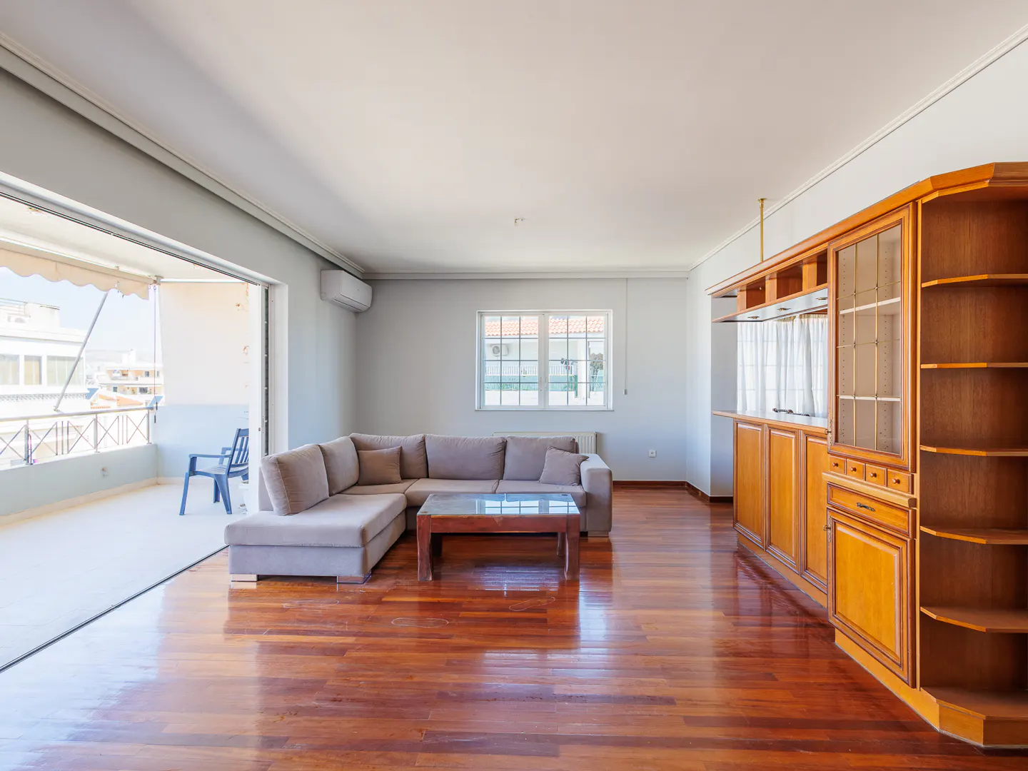 Spacious living room with hardwood floors, a grey sectional sofa, coffee table, and a large wooden built-in bar unit.