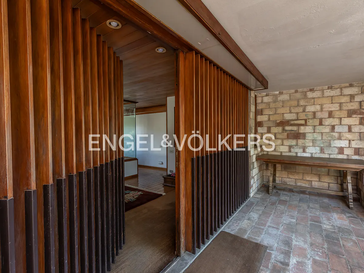 Interior view of a home with a wooden slat wall and brick wall with a wooden bench.