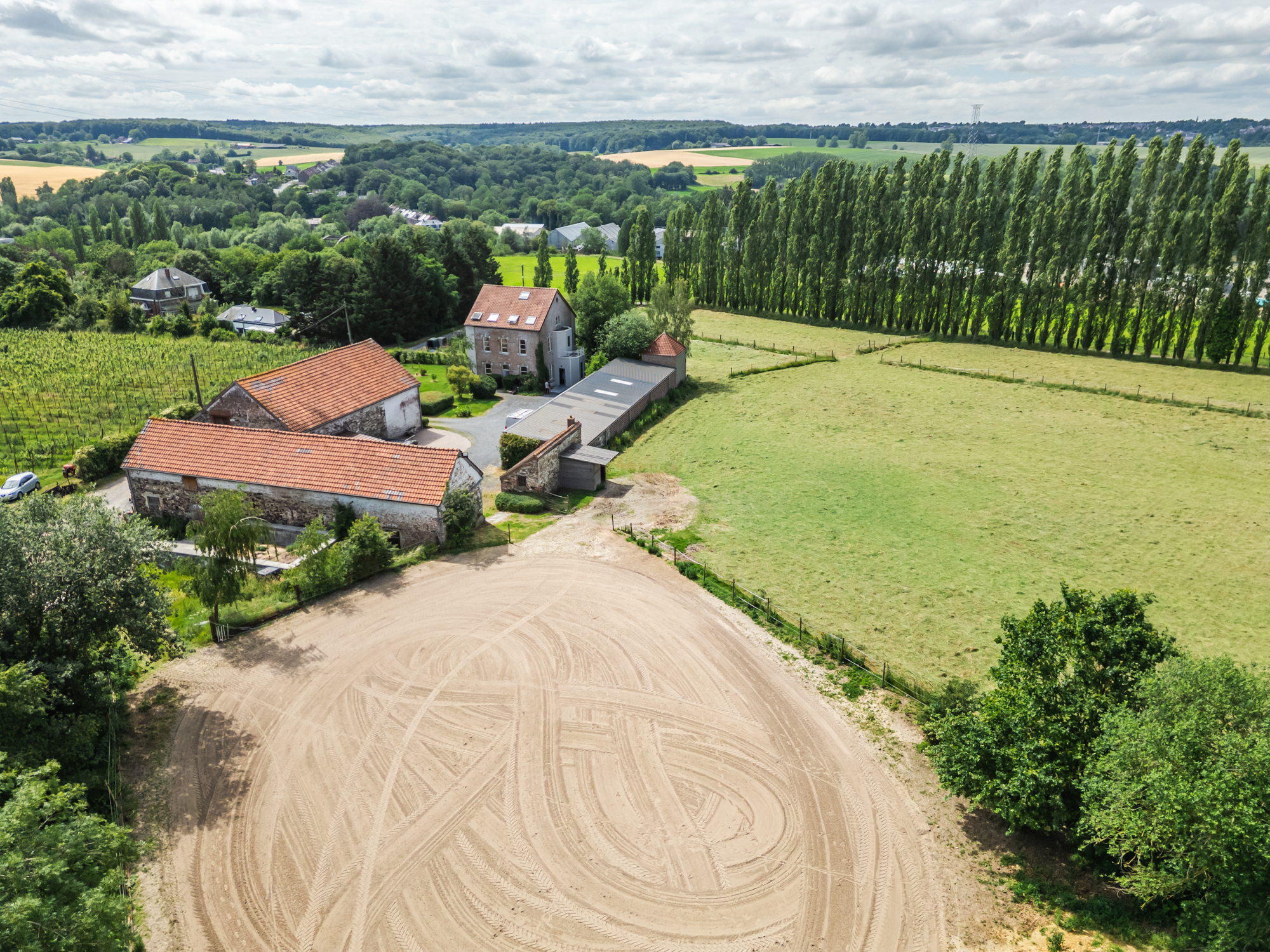 Propriété équestre avec piste et écuries au milieu des champs