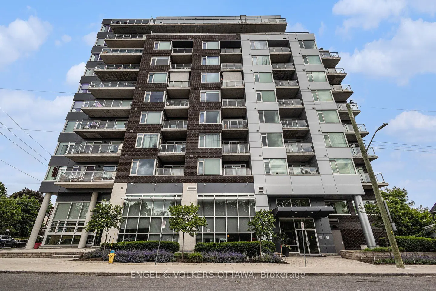 Exterior view of a modern, multi-story condo building with balconies, large windows, and a gray and brown facade.
