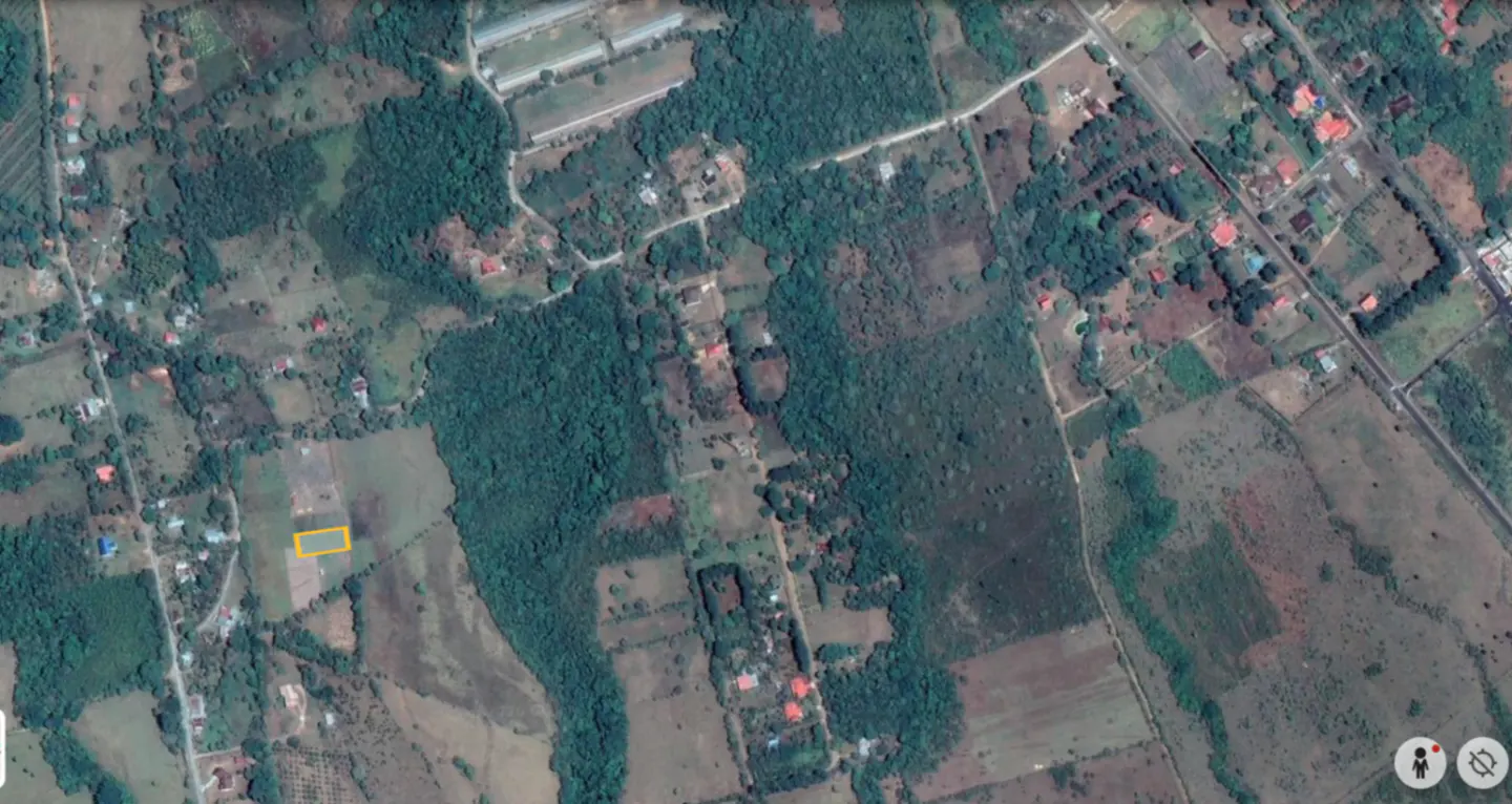 Aerial view of a rural landscape with green trees, fields, and a yellow outlined plot of land.