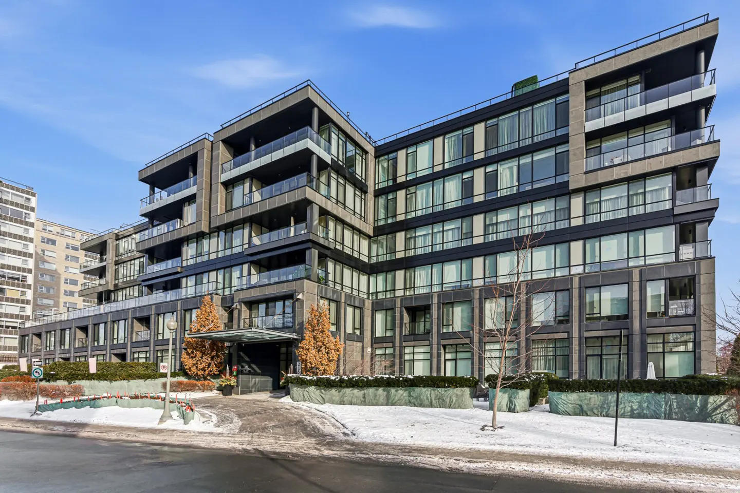 Modern condo building with black trim and glass balconies on a snowy day.