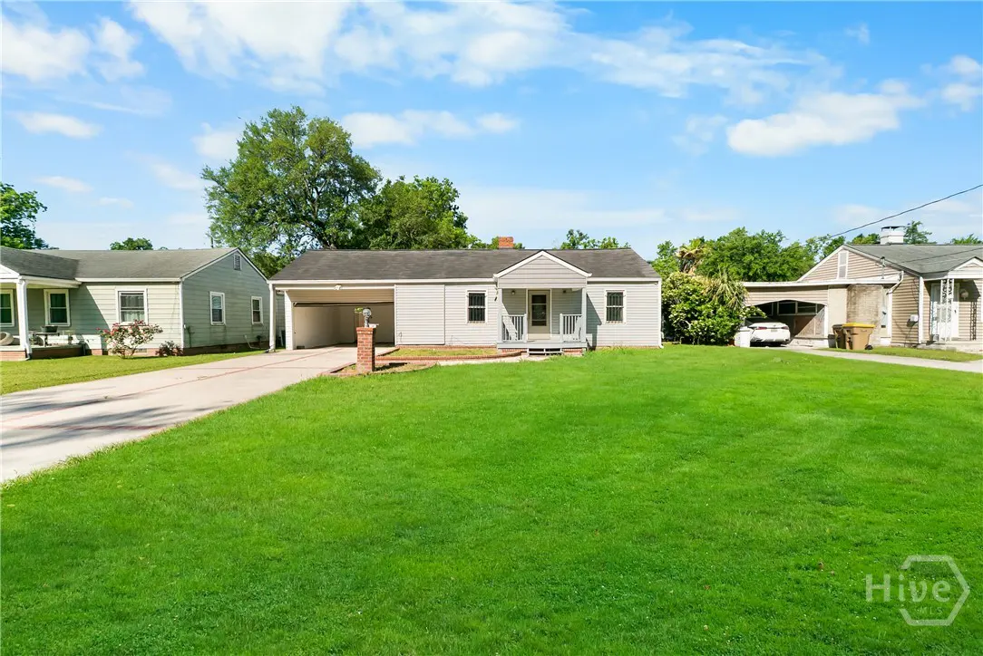 A light gray single-story house with a green lawn and blue sky.