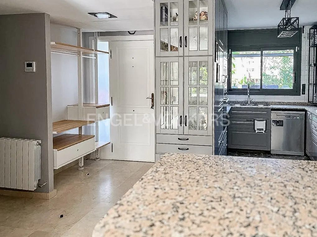 A bright apartment interior with a white door, open closet, and gray kitchen cabinets. A granite countertop is in the foreground.