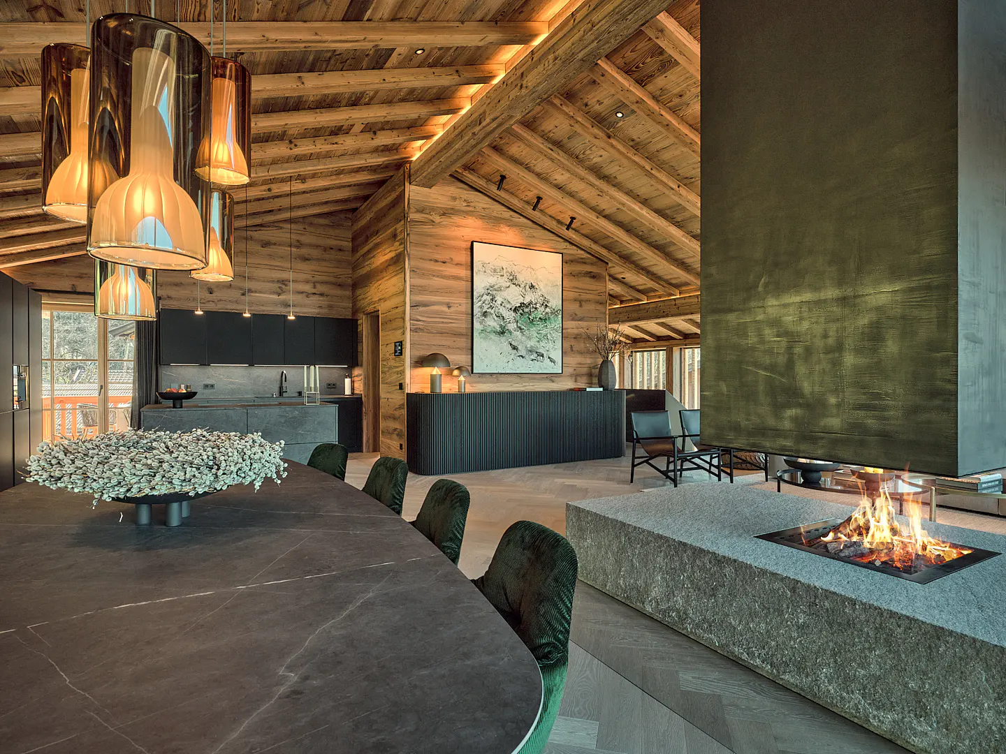 A modern chalet interior with wood walls, a stone fireplace, and a black marble table with green velvet chairs.