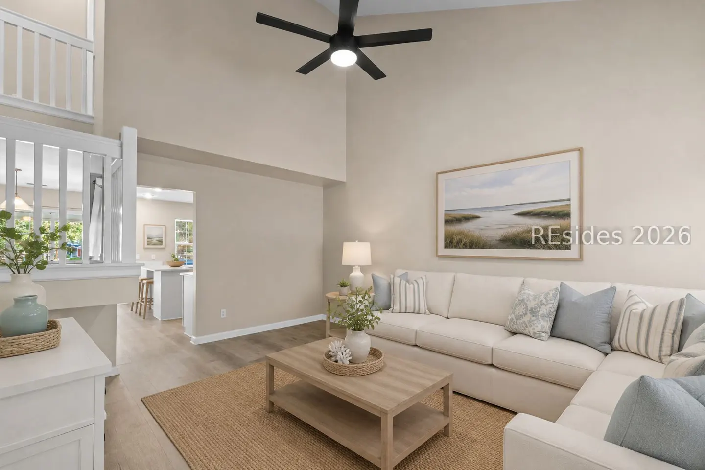 Bright living room with a white sectional sofa, jute rug, and a light wood coffee table. A black ceiling fan is overhead.