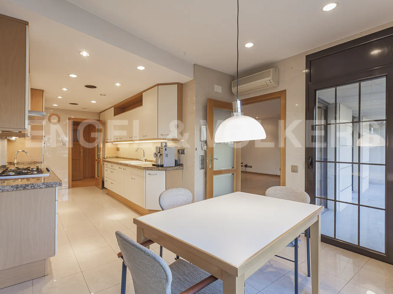 Modern kitchen with white cabinets, granite countertops, and a dining area featuring a white table and grey chairs.