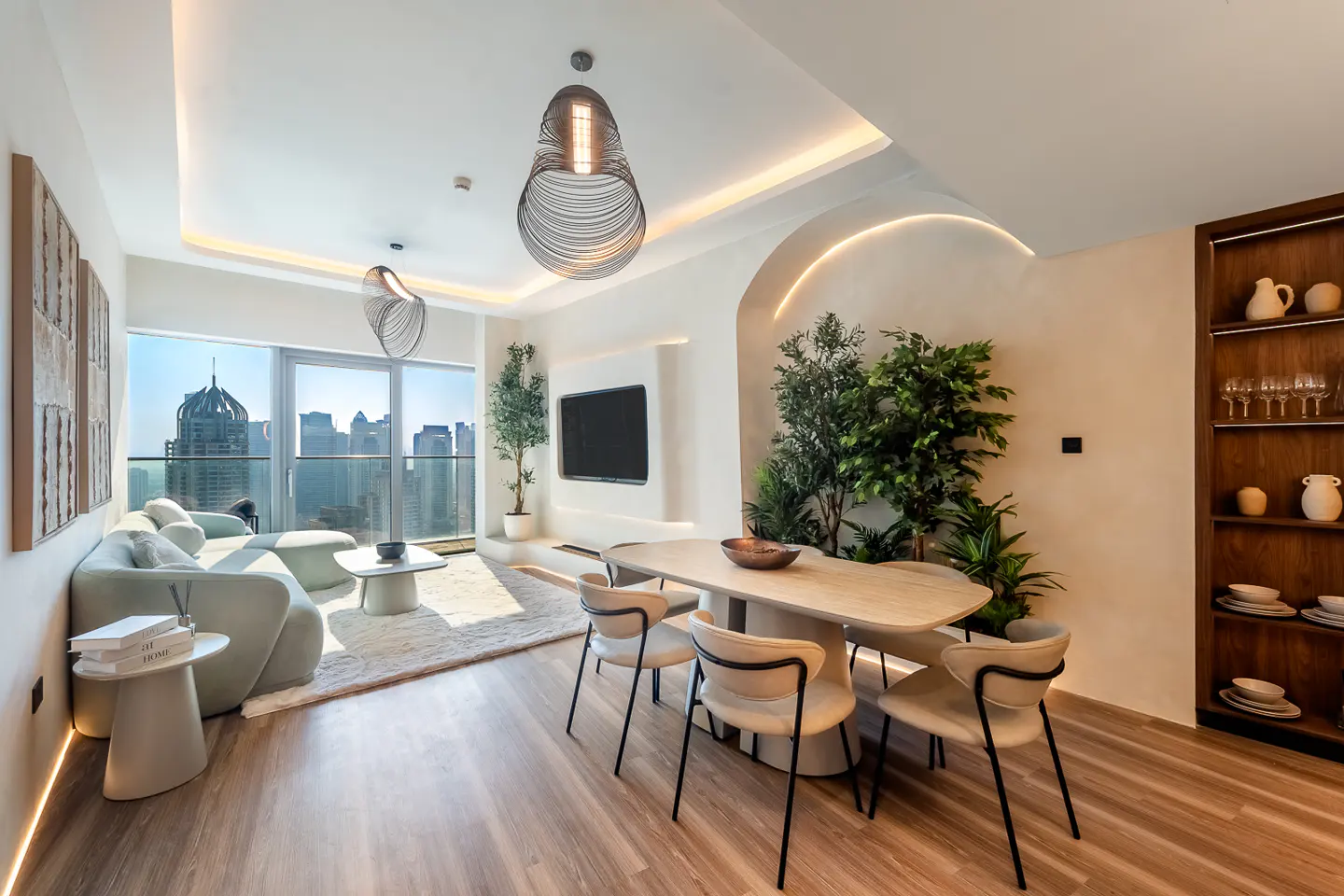 Bright, modern apartment interior with a light green sofa, dining table, and city view through a large window.