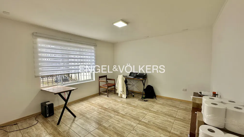 Bright room with tile floor, desk, chair, and window with blinds. Engel & Völkers logo is visible.