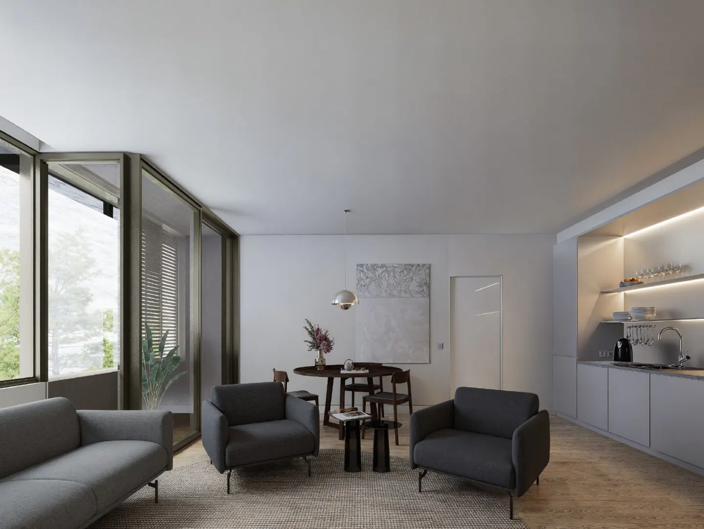 A modern living room with gray sofa and chairs, a round dining table, and a kitchen area with illuminated shelves.