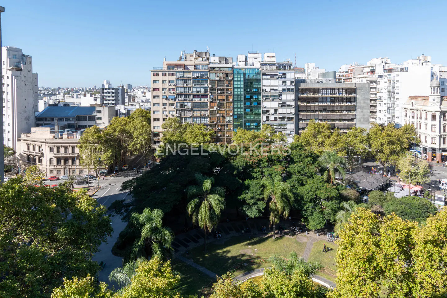 Cityscape view with green park, tall buildings, and blue sky. Engel & Volkers logo visible.