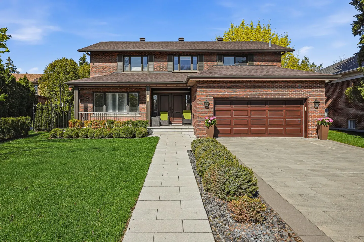 Two-story brick house with a brown roof, a two-car garage, and a stone walkway leading to the front door.