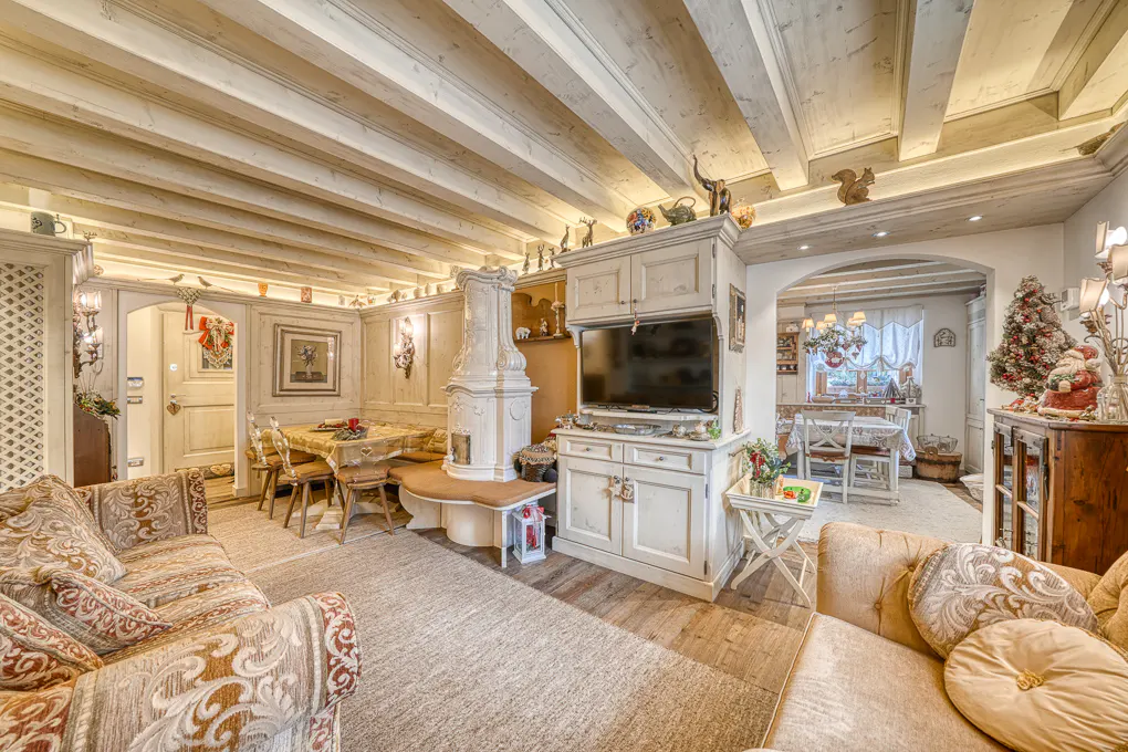 Living room with beamed ceiling, sofas, TV, and dining area. The room is decorated for Christmas.