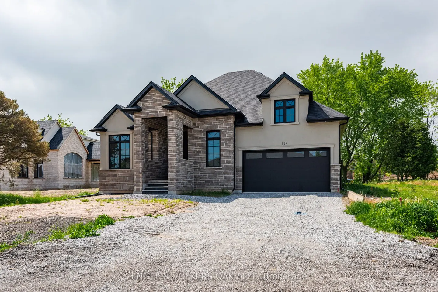 A modern two-story house with a gray stone facade and a black garage door.