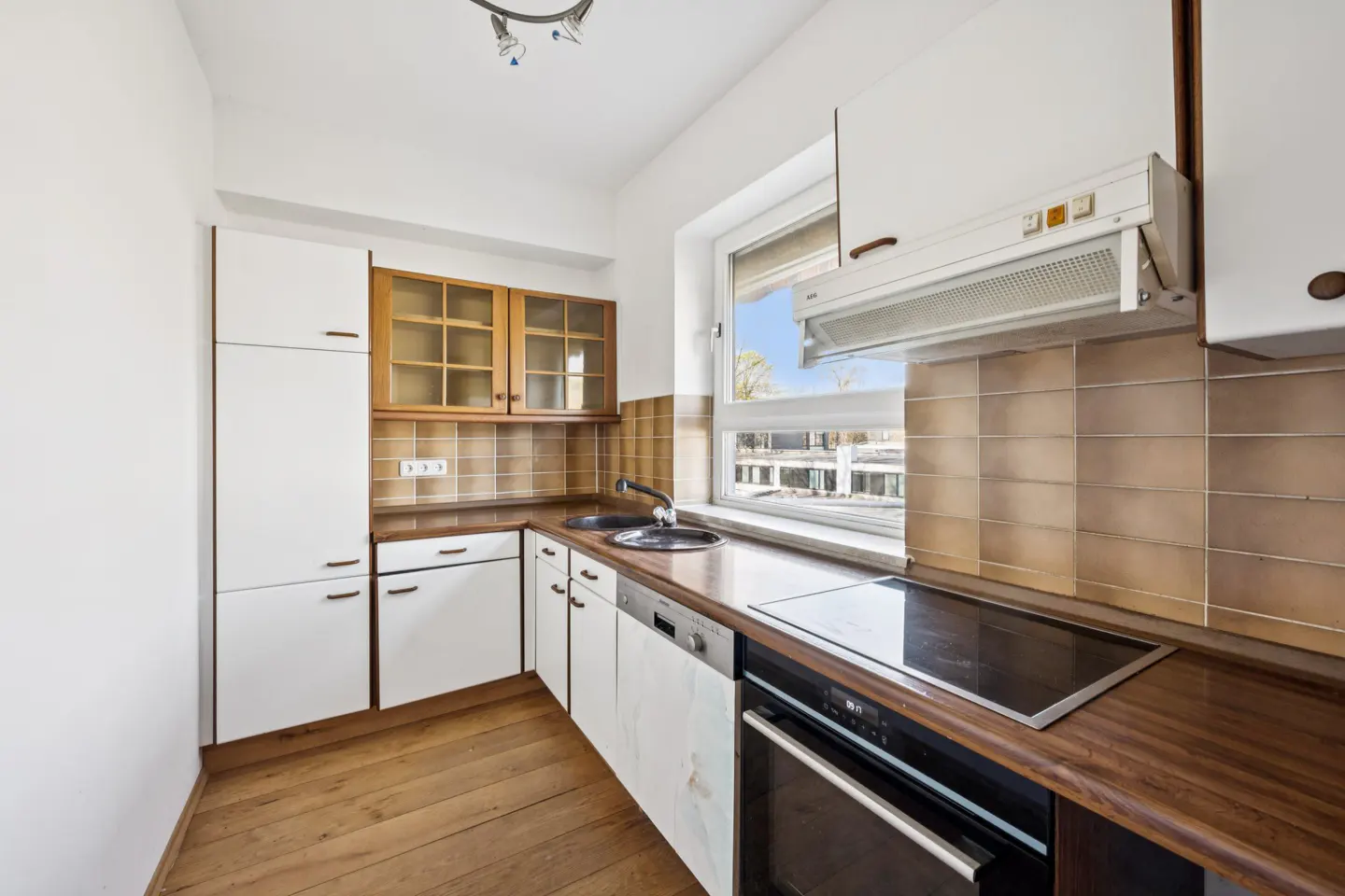 A bright kitchen with white cabinets, wood countertops, and a window. Appliances include a stove, oven, and dishwasher.