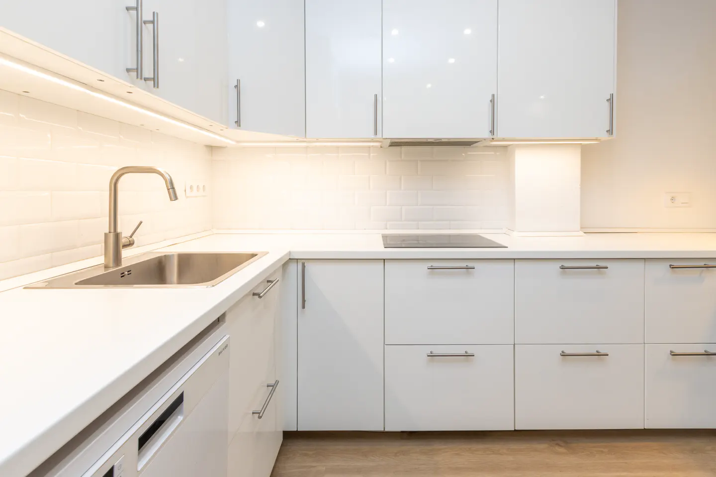 Bright, modern kitchen with white cabinets, stainless steel sink and faucet, and white subway tile backsplash.