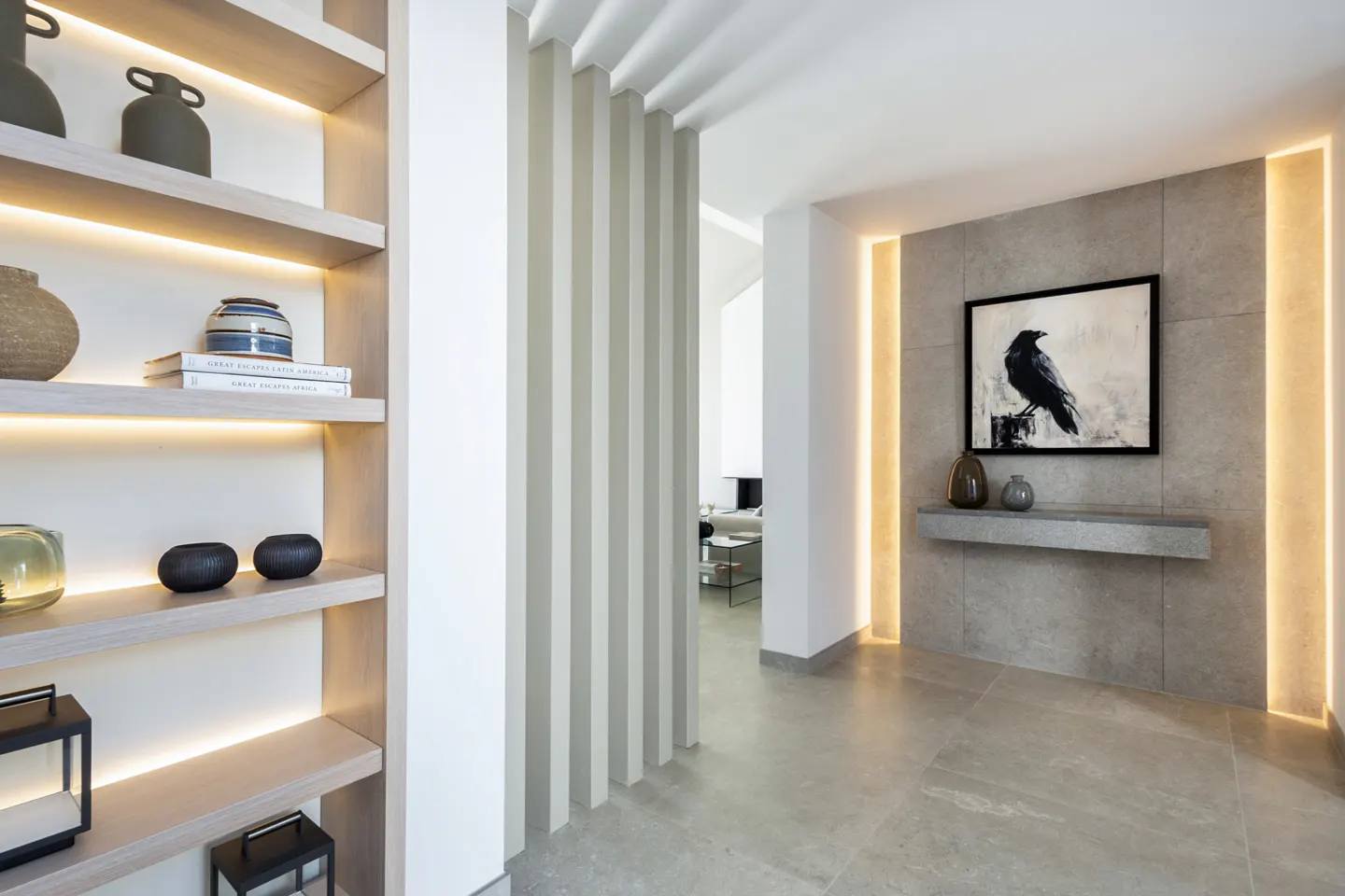 Modern hallway with illuminated wood shelving, vertical wall slats, and a stone accent wall featuring a raven art piece.