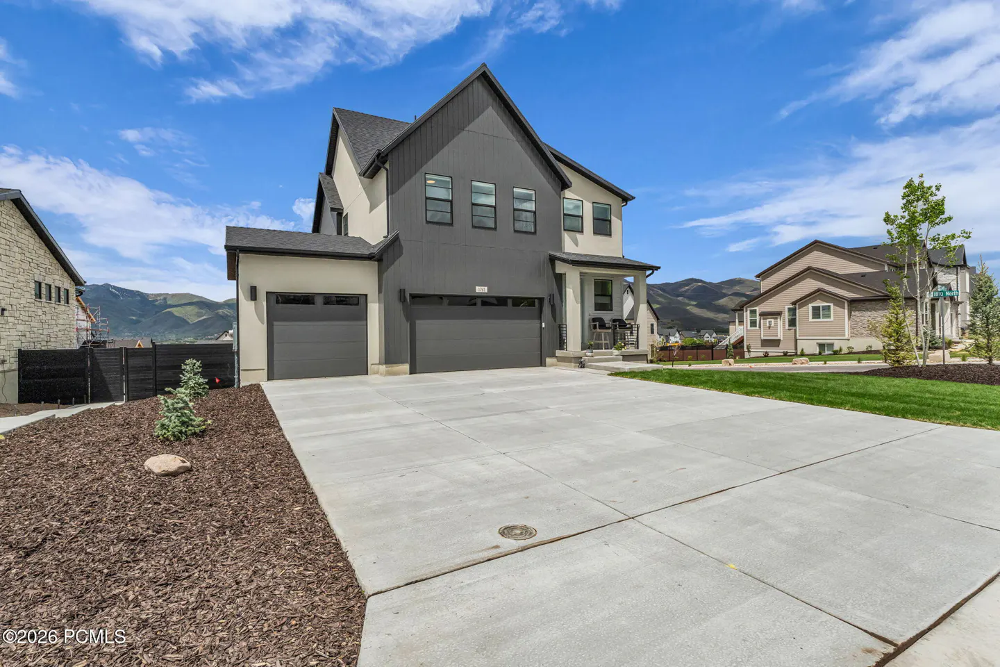 Two-story home with gray siding, a two-car garage, and a concrete driveway on a sunny day.