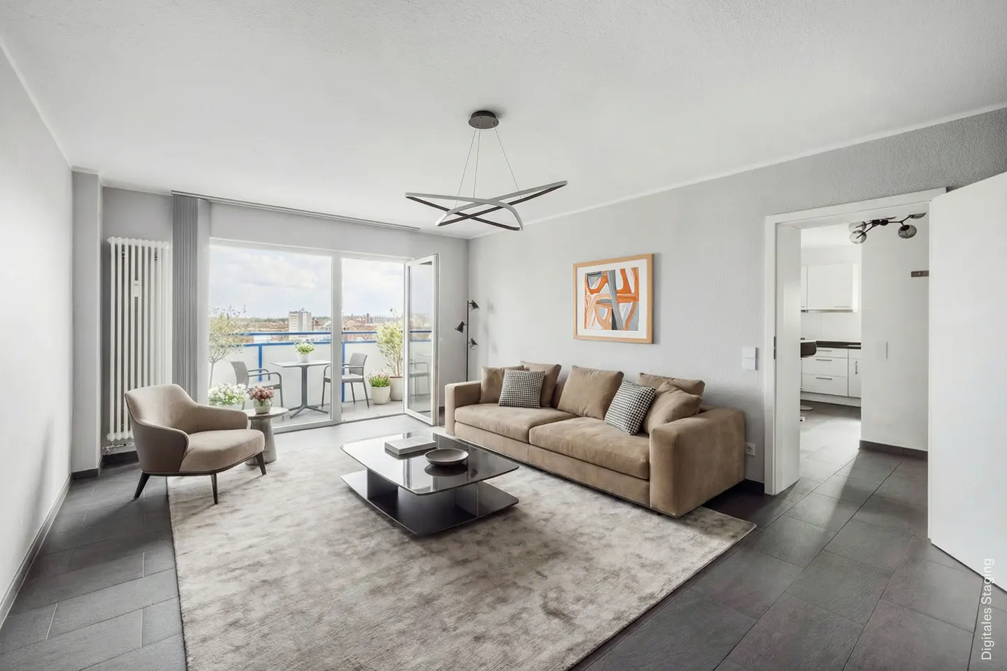 Living room with a beige sofa, armchair, and glass table on a gray rug. Balcony with table and chairs visible through sliding glass doors.
