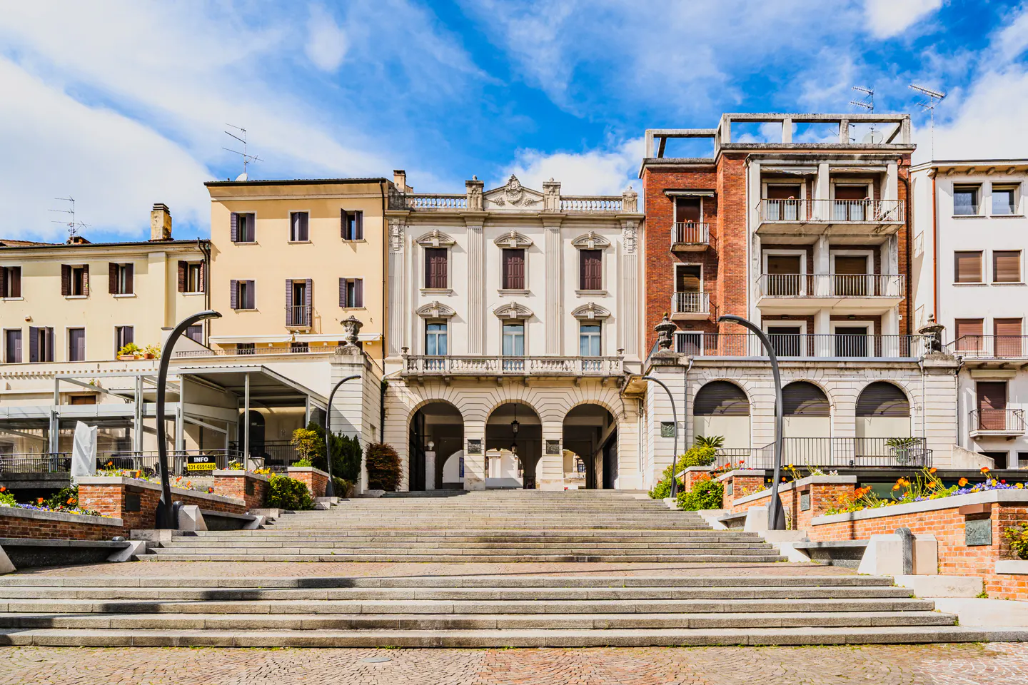 Wide shot of a grand staircase leading to European-style buildings under a blue sky with clouds.
